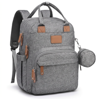Diaper bag backpack hanging from a stroller handle using integrated attachment straps