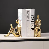 Gold ceramic statue bookends supporting books on a shelf