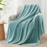 Soft celadon fleece blanket draped over couch