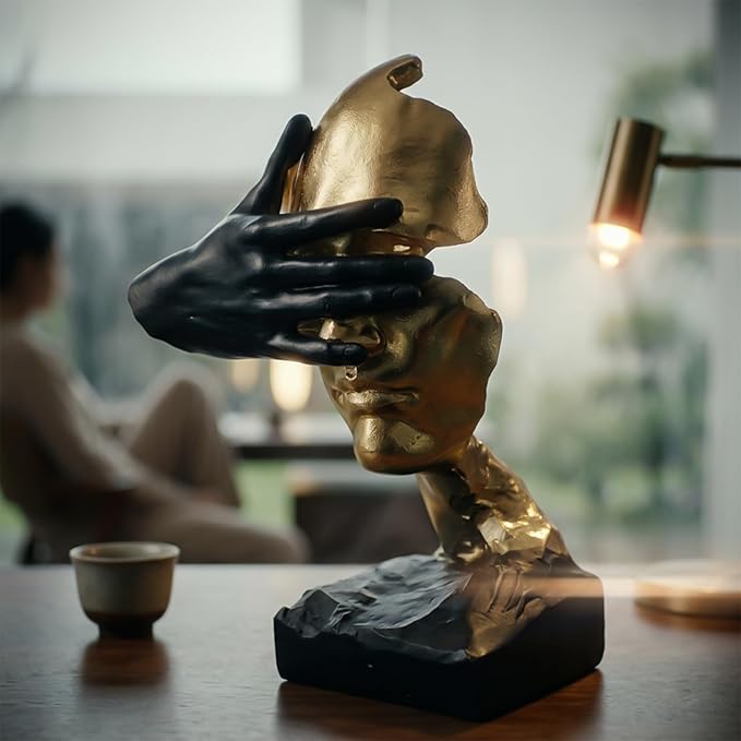 Gold abstract face sculpture arranged with books on a contemporary living room shelf
