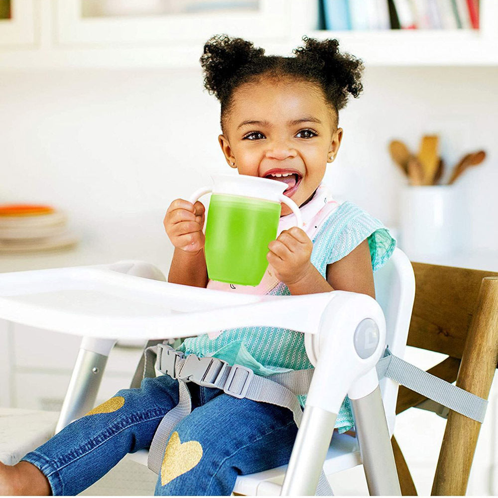 toddler drinking from spill proof sippy cup while sitting in high chair