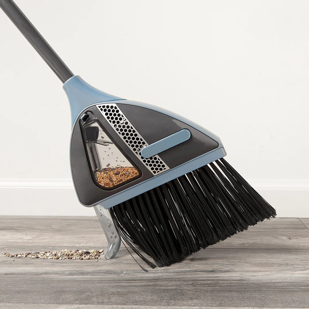 Vacuum broom collecting dust from a hard floor surface