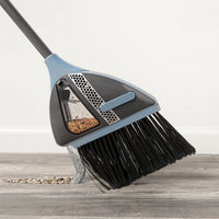Vacuum broom collecting dust from a hard floor surface