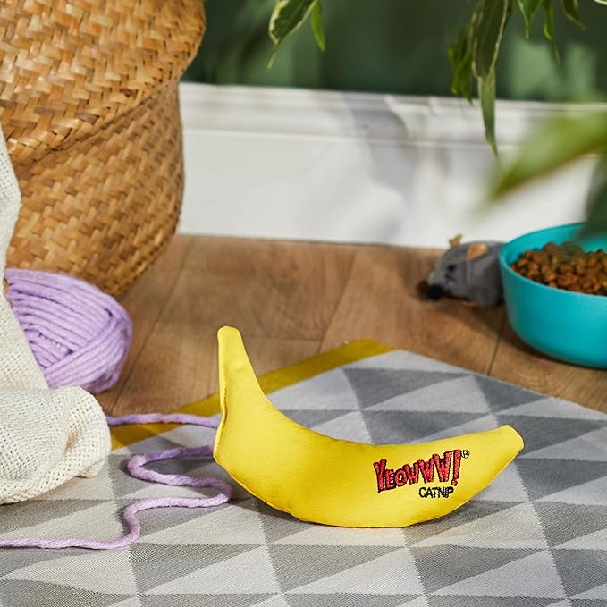 Cat holding and batting the yellow banana catnip toy